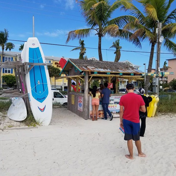 a group of people on a beach holding a surf board