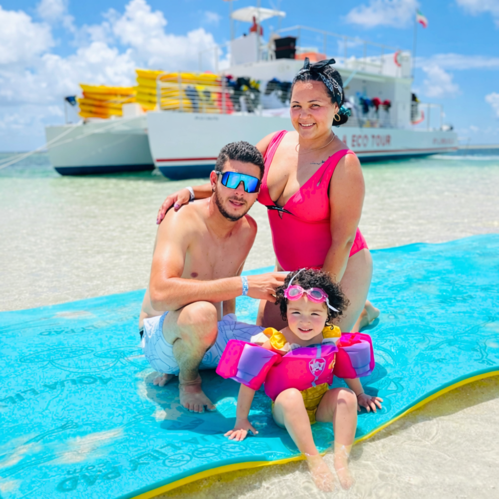 Family relaxing on a float in shallow turquoise water at a Key West sandbar with a Sunset Watersports boat in the background.